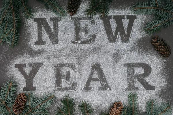 Top view of New Year lettering in frame of spruce branches and pine cones — Stock Photo