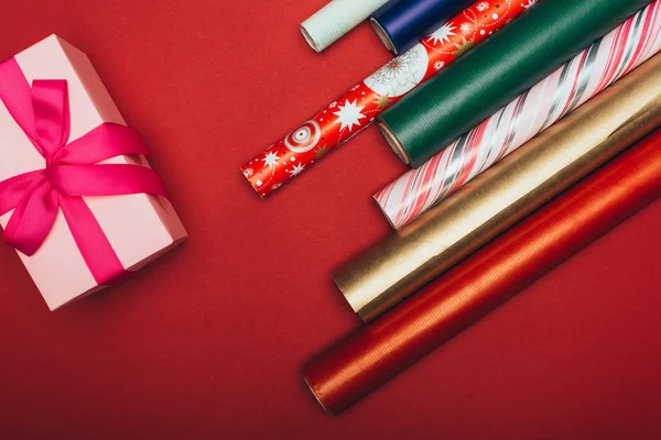 Top view of wrapping paper rolls and christmas gift box on red — Stock Photo