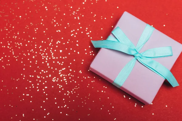 Vista superior de um presente de Natal com confete dourado no vermelho — Fotografia de Stock