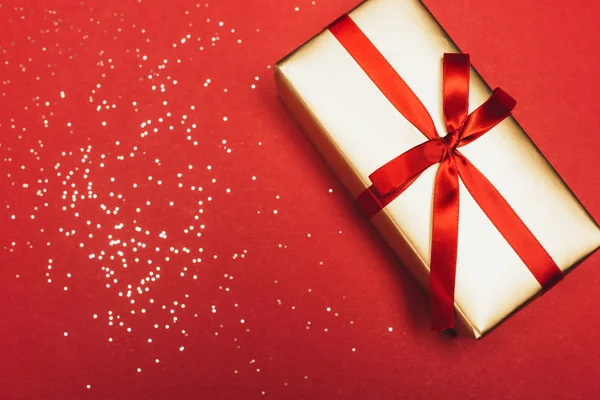 Верхний вид на традиционное Рождество подарок с золотыми конфетти на красный — стоковое фото