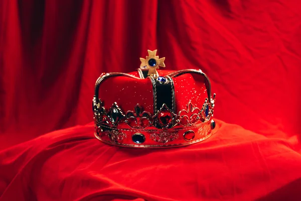 Ancient golden crown with gemstones on red cloth — Stock Photo