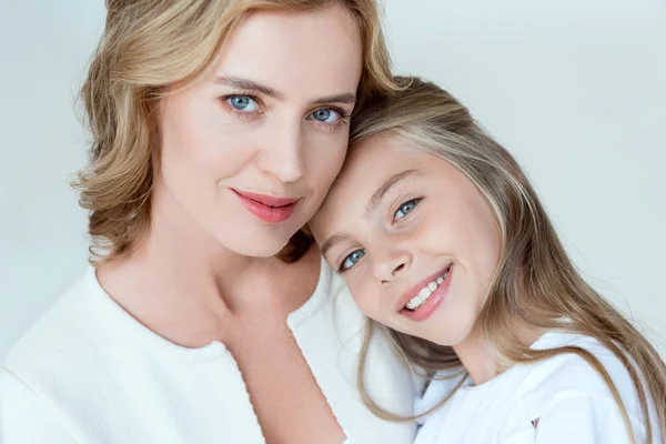 Atractiva madre e hija sonriente mirando a la cámara aislada en gris - foto de stock