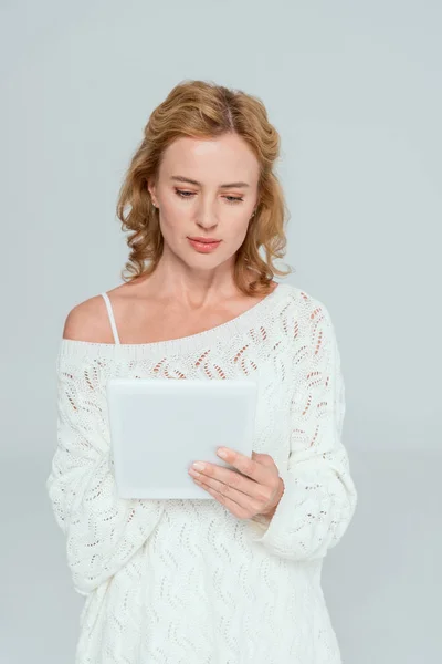 Attractive woman in sweater using digital tablet isolated on grey — Stock Photo