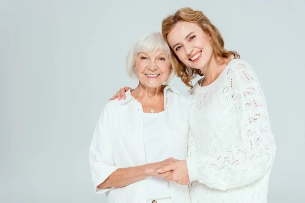 Attractive daughter hugging smiling mother and looking at camera isolated on grey — Stock Photo