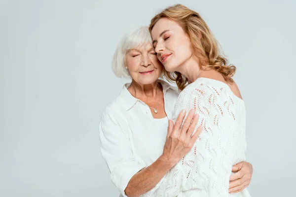 Attractive daughter with closed eyes hugging mother isolated on grey — Stock Photo