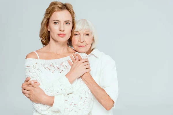 Attractive mother hugging daughter and looking at camera isolated on grey — Stock Photo