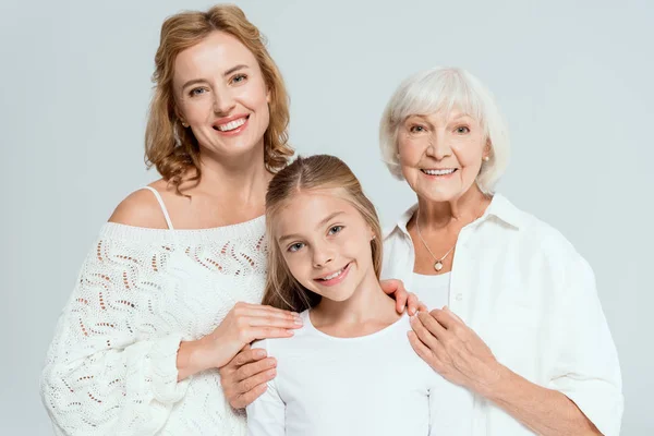 Smiling mother and grandmother hugging granddaughter isolated on grey — Stock Photo