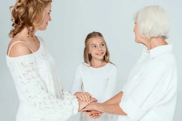 Smiling mother, grandmother and granddaughter holding hands isolated on grey — Stock Photo