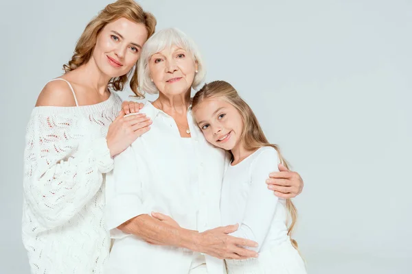 Sorridente nipote, madre e nonna che si abbracciano isolate sul grigio — Foto stock