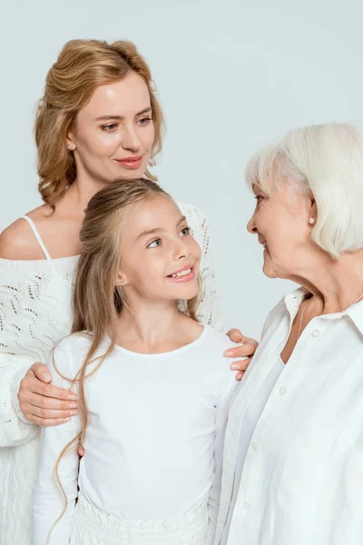 Smiling granddaughter, mother and grandmother looking at each other isolated on grey — Stock Photo