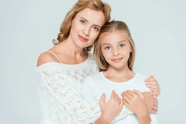 Attractive mother hugging smiling daughter and looking at camera isolated on grey — Stock Photo