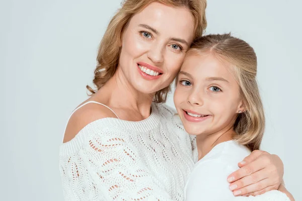 Attraktive Mutter umarmt lächelnde Tochter und blickt isoliert in die Kamera auf grau — Stockfoto