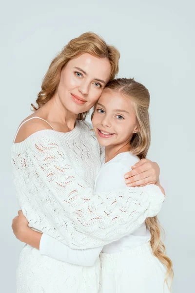 Attractive mother hugging smiling daughter and looking at camera isolated on grey — Stock Photo