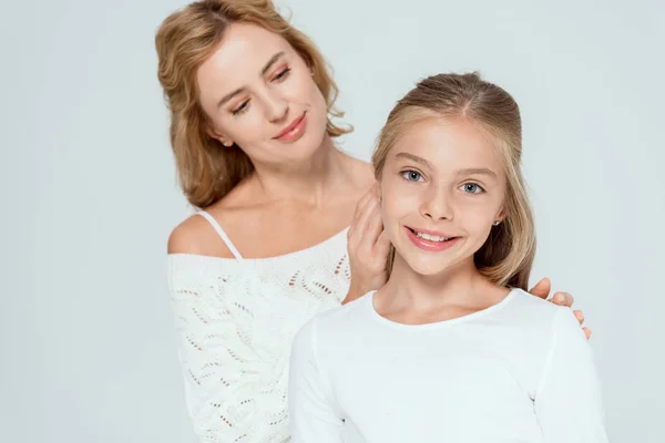 Приваблива мати в светрі обіймає усміхнену дочку ізольовано на сірому — стокове фото
