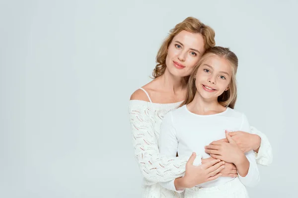 Attractive mother hugging smiling daughter and looking at camera isolated on grey — Stock Photo