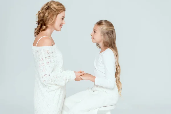 Visão lateral da mãe atraente segurando as mãos da filha sorridente isolada no cinza — Fotografia de Stock