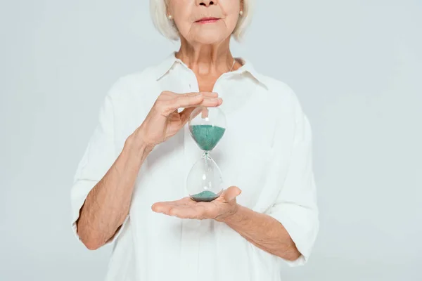 Vista recortada de la mujer sosteniendo reloj de arena aislado en gris - foto de stock