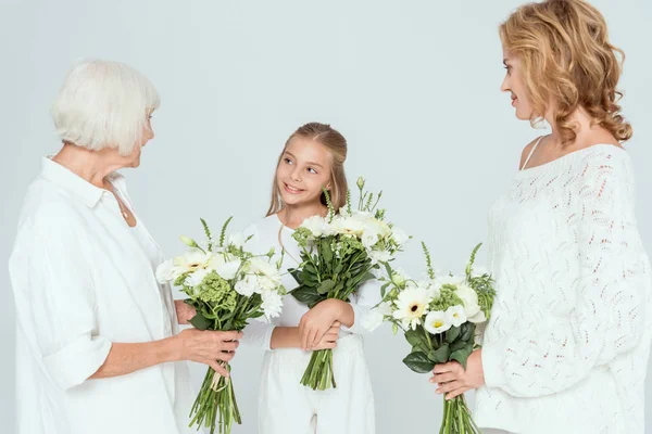 Souriant petite-fille, mère et grand-mère tenant des bouquets isolés sur gris — Photo de stock