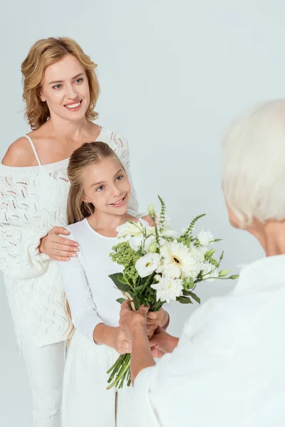 Sorridente nipote dando bouquet alla nonna isolata su grigio — Foto stock