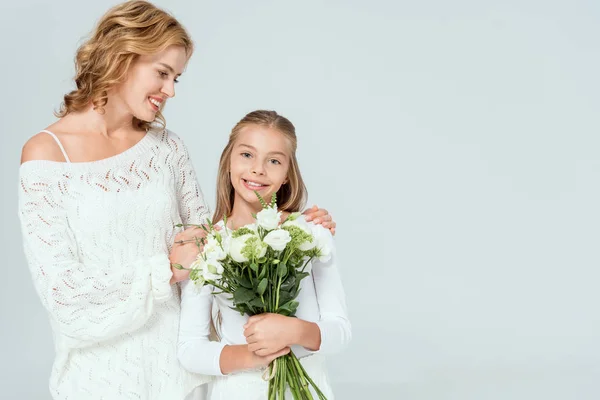 Attraente madre abbraccio sorridente figlia con bouquet isolato su grigio — Foto stock