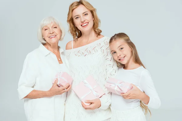 Smiling granddaughter, mother and grandmother holding gifts isolated on grey — Stock Photo