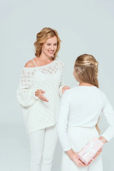 Back view of daughter with gift looking at smiling mother isolated on grey — Stock Photo