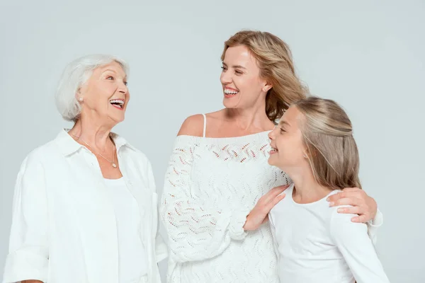 Smiling mother hugging granddaughter and looking at grandmother isolated on grey — Stock Photo