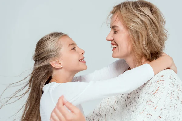 Seitenansicht von lächelnder Mutter und Tochter, die sich isoliert auf grau umarmen — Stockfoto