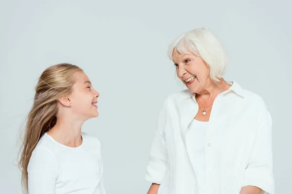 Petite-fille et grand-mère souriantes se regardant isolées sur du gris — Photo de stock