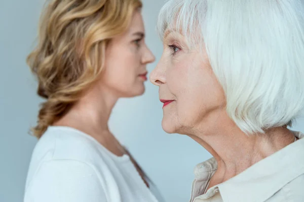 Enfoque selectivo de la madre y la hija en el fondo aislado en gris - foto de stock