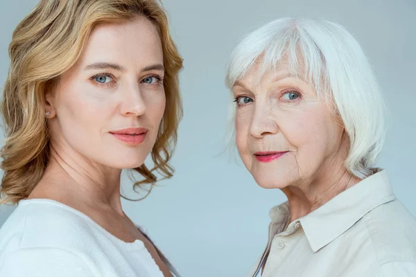 Attractive mother and daughter looking at each other isolated on grey — Stock Photo