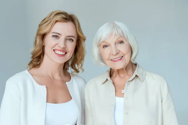 Smiling mother and daughter looking at camera isolated on grey — Stock Photo