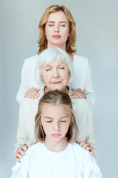 Granddaughter, grandmother and mother with closed eyes hugging isolated on grey — Stock Photo
