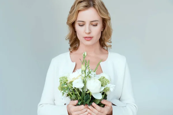 Attrayant femme tenant bouquet et regardant vers le bas isolé sur gris — Photo de stock