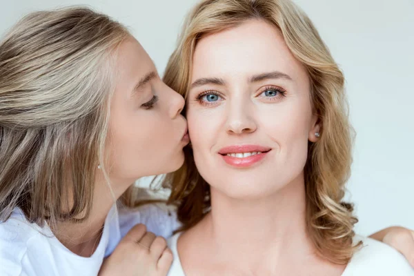 Cute daughter kissing smiling and attractive mother isolated on grey — Stock Photo