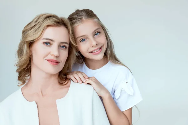 Atractiva madre e hija sonriente mirando a la cámara aislada en gris - foto de stock