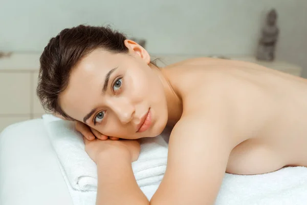 Attrayant femme regardant caméra et couché sur la table de massage dans le spa — Photo de stock