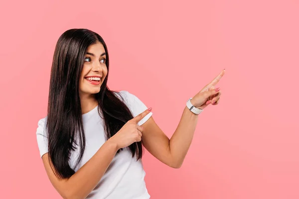 Lächelndes hübsches brünettes Mädchen zeigt mit den Fingern auf Kopierraum isoliert auf rosa — Stockfoto