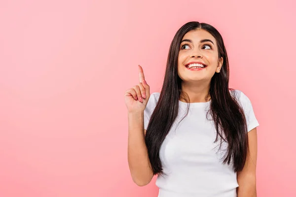 Excited pretty brunette girl pointing with finger at copy space isolated on pink — Stock Photo