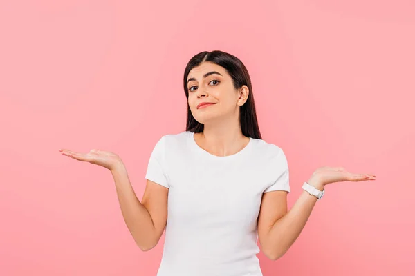 Sorrindo menina morena bonita mostrando gesto de encolher de ombros isolado em rosa — Fotografia de Stock