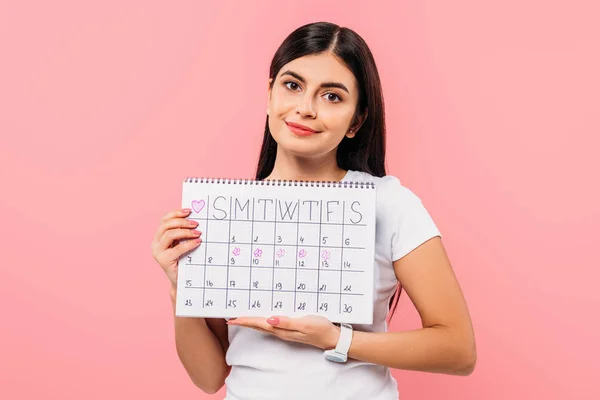 Sonriente bonita chica morena celebración período calendario aislado en rosa - foto de stock