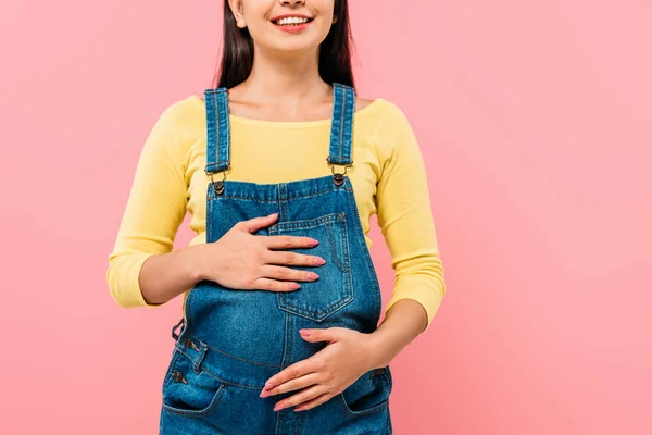 Abgeschnittene Ansicht von schwangeren hübschen Mädchen berühren Bauch isoliert auf rosa — Stockfoto