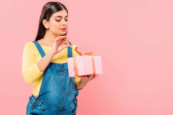 Pregnant pretty girl unwrapping gift isolated on pink — Stock Photo