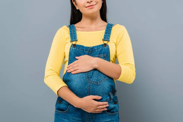 Partial view of smiling pregnant pretty girl touching belly isolated on grey — Stock Photo