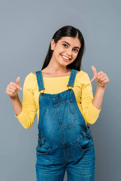 Smiling pregnant pretty girl pointing with fingers at belly isolated on grey — Stock Photo