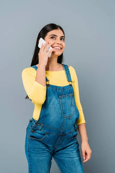 Усміхнена красива дівчина говорить на смартфоні ізольовано на сірому — стокове фото