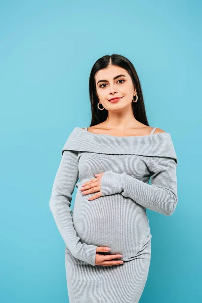 Smiling pregnant pretty girl touching belly isolated on blue — Stock Photo