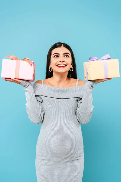 Sonriente embarazada bonita celebración regalos aislado en azul - foto de stock