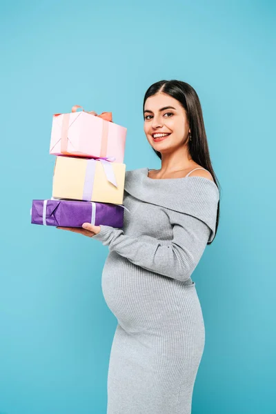 Sonriente embarazada bonita celebración regalos aislado en azul - foto de stock