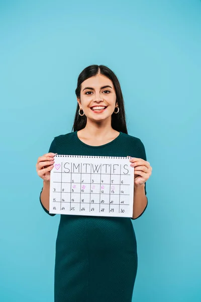 Sorridente grávida menina segurando calendário período isolado no azul — Fotografia de Stock